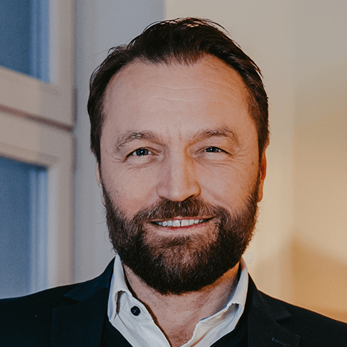 Lächelnde Person im Anzug mit Bart – Business-Porträt.