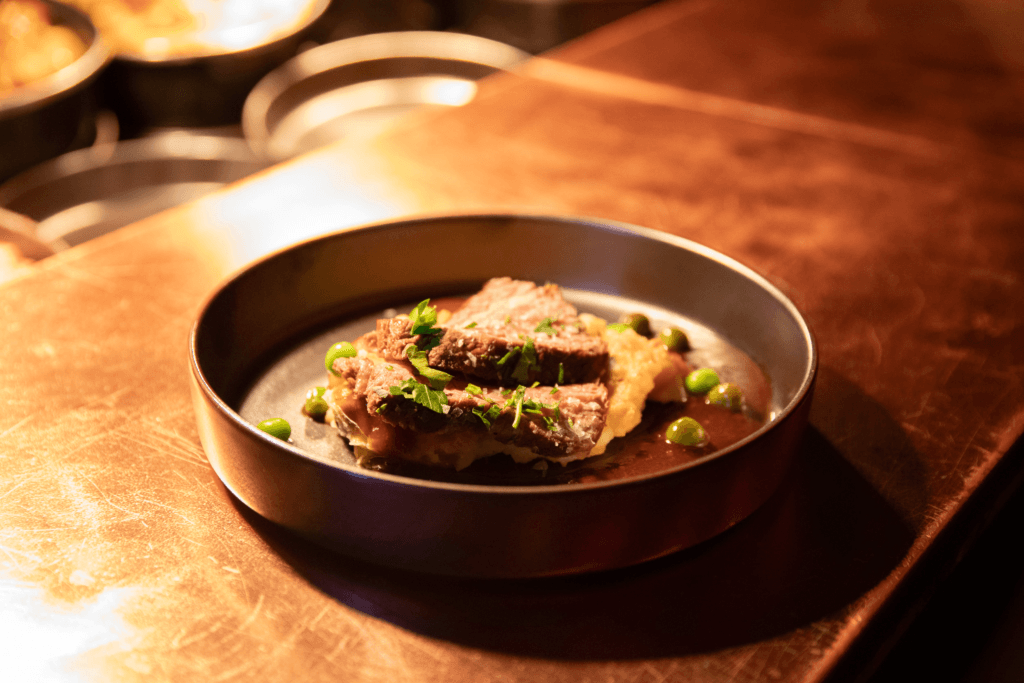 Gepflegter Steak auf Kartoffelpüree mit Erbsen und Petersilie – feines Restaurantgericht.