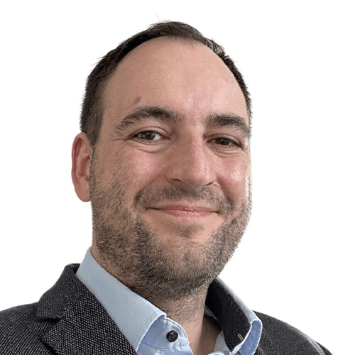 Porträt eines lächelnden Mannes in Blazer und Hemd vor weißem Hintergrund.